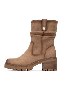 Botín de ante marrón con puño doblado, punta redonda y tacón de bloque texturizado. Cuenta con un detalle de botón decorativo y suela de goma.