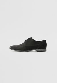 Chaussure noire à bout pointu, présentant une texture striée, des accents lisses et un talon bas. Le design est élégant et moderne.