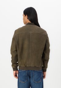 Giacca bomber verde oliva realizzata in pelle texture, con colletto e polsini a coste, vita aderente e dettagli di cucitura sul retro.