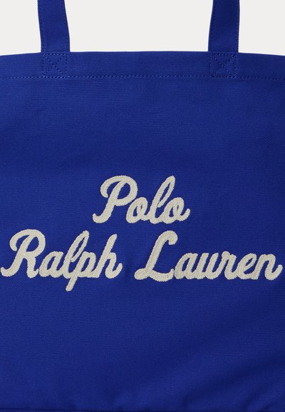 Τσάντα ώμου από μπλε ύφασμα με λευκή κεντημένη επιγραφή «Polo Ralph Lauren» και δύο ραμμένες λαβές στο επάνω μέρος.