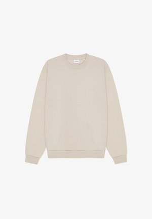 Bēša krāsas džemperis no mīksta auduma ar apaļu kaklu, garām piedurknēm un nelielu izšuvumu logotipu priekšpusē.