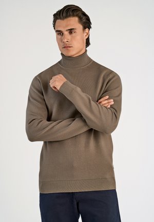 Bruine gebreide coltrui met geribbelde manchetten en zoom, met een gladde textuur en lange mouwen, gedragen over een donkere broek.