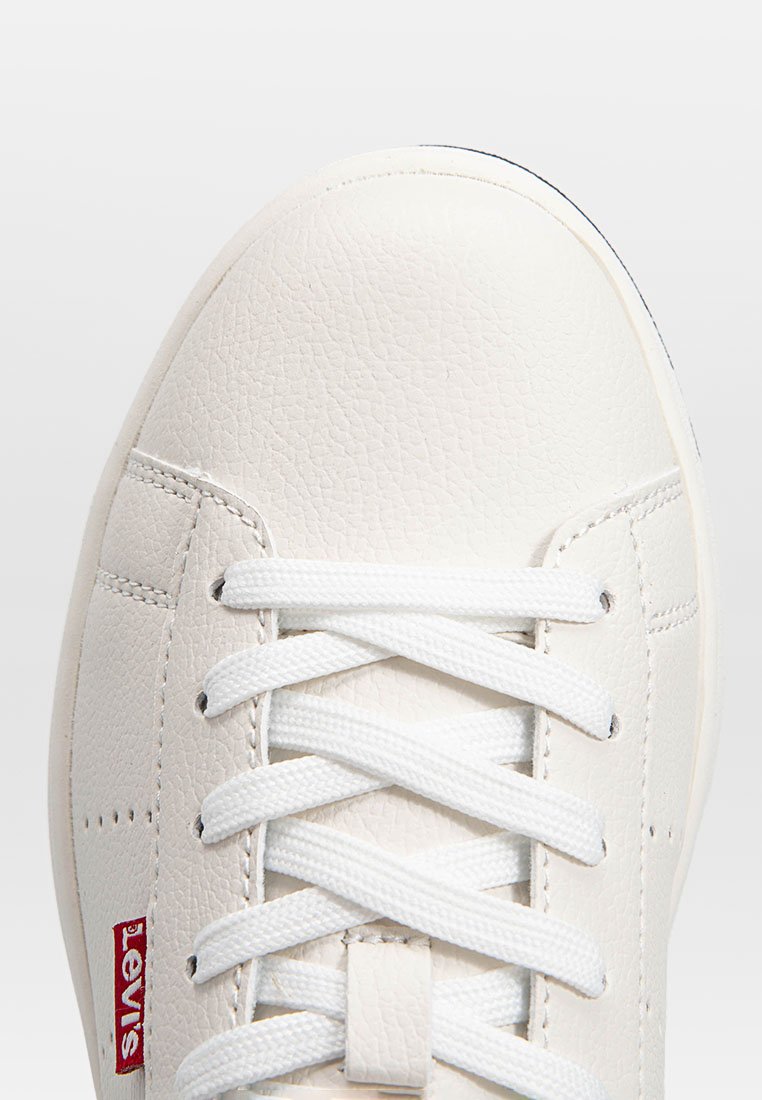 Zapatilla blanca fabricada en cuero texturizado, con cordones blancos, un logo rojo de Levi's y una puntera redondeada. Diseño minimalista con costuras sutiles.