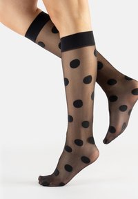 Calze al ginocchio nere con motivo, realizzate in materiale trasparente, caratterizzate da grandi pois neri su uno sfondo trasparente e una fascia nera solida.