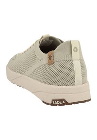 Beige mesh sneaker with a textured surface, white midsole, and brown rubber outsole; features a tan logo patch and back accent.
