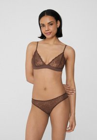 Bruine kanten bralette met dunne bandjes en afgebiesde randen; bijpassende bruine kanten string; ingewikkeld bloemmotief overal. Gladde textuur.