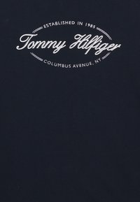 T-shirt in cotone blu navy con testo del logo bianco. Il design include una cornice ovale con "Fondato nel 1985" e "Columbus Avenue, NY."