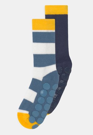 Colorful socks featuring a combination of blue, white, and yellow stripes on one sock, and solid navy with textured grip dots on the other.