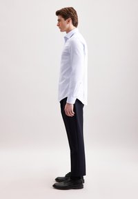 Camicia a maniche lunghe azzurro chiaro con vestibilità slim e colletto con bottoni, abbinata a pantaloni neri su misura e scarpe in pelle nere.