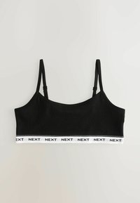 Crna bralette sa podesivim trakama, mekanim materijalom i bijelom elastičnom trakom na kojoj je ponavljano ispisano "NEXT" duž donjeg ruba.