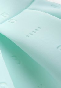 Minzgrüner Stoff mit glatter Textur, verziert mit erhabenem Schriftzug, gefaltet, um sein Design und Materialdetails zu zeigen.