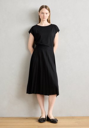 Black short-sleeve top paired with a black pleated skirt, featuring a smooth texture and ankle-length design. Worn with black flat shoes.