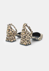 Leopard-print heeled shoes with a textured fabric, square heels, ankle strap, and open back design.