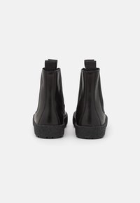 Černé kotníkové boty vyrobené z hladké kůže, s texturovanou černou podrážkou a poutky na zadní straně pro snadné obouvání. Minimalistický design.