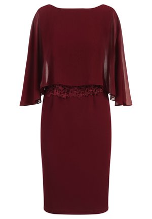Robe bordeaux avec un voile transparent et des détails en dentelle à la taille. Tissu lisse et forme ajustée, avec des manches courtes qui tombent délicatement.