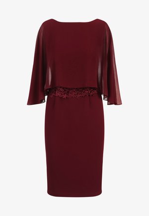 Robe bordeaux avec un voile transparent et des détails en dentelle à la taille. Tissu lisse et forme ajustée, avec des manches courtes qui tombent délicatement.