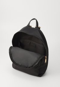 Zaino nero realizzato in nylon liscio con una forma arrotondata. Presenta accessori in tono dorato, una tasca principale con zip e una tasca interna.