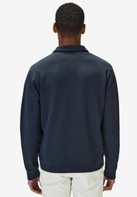 Mörkblå sweatshirt med långa ärmar, rundad hals och ribbade muddar. Mjuk textur med en enkel design, i en solid färg utan mönster.