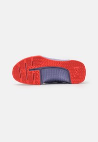 Semelle d'une basket avec une bande de roulement rouge et un soutien médio-pied noir, présentant un motif texturé et un logo "X" près du talon.