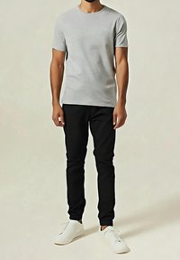 Camiseta gris de manga corta, pantalones ajustados negros y zapatillas blancas. La camiseta está hecha de una tela suave, que ofrece un look casual.
