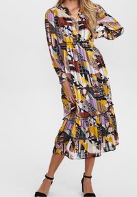 Robe longue colorée imprimée de motifs géométriques, avec devant boutonné, taille élastique et ourlet à volants, réalisée en tissu léger.