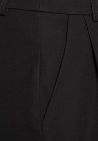 Svarta plisserade byxor gjorda av texturerad tyg, med en slät midja och skarpa veck som betonar den skräddarsydda designen.