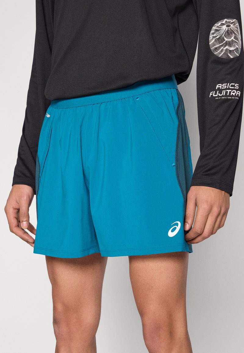 Shorts de sport bleu sarcelle avec un tissu léger et respirant. Comprend des poches latérales et un logo ASICS. Assorti à un shirt à manches longues noir.