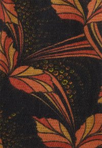 Textile featuring a vibrant floral pattern with orange, yellow, and black colors. The fabric has a soft texture and visible details in the design.