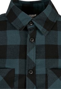 Karierte Flanellhemd in Türkis und Schwarz. Verfügt über einen spitzen Kragen, schwarze Knöpfe und zwei Brusttaschen. Die Textur ist weich und gewebt.