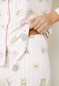 Set de pijama din bumbac cu dungi roz și albe, împodobit cu diverse ilustrații cu câini, bluză cu nasturi și pantaloni cu talie elastică.