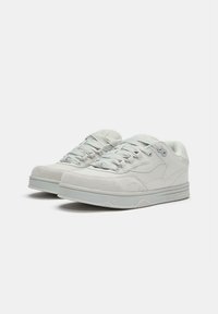 Sneaker grigio chiaro con tomaia in camoscio morbido, linguetta in mesh testurizzato, lacci piatti e suola ammortizzata. Presenta dettagli di branding discreti.
