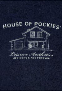 Marineblauwe handdoek met een gestructureerd oppervlak, met witte geborduurde tekst: "HOUSE OF POCKIES," een huisillustratie en "Leisure Aesthetics."