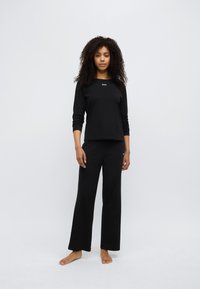 Must pikkade varrukatega särk ja püksid, millel on ümar kaelus, lihtne "BOSS" logo, pehme kangas ja lõdvestunud lõige.