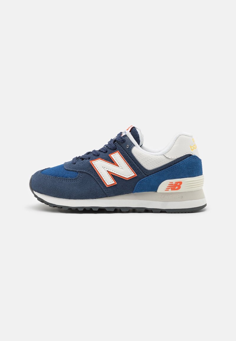 Baskets New Balance bleu marine et blanches avec logo "N" orange, tige en suède et mesh, semelle intermédiaire blanche et semelle extérieure noire.