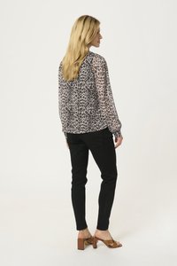 Blouse à imprimé animal en tissu léger, jeans skinny noirs et sandales à talons marron. Manches longues et coupe décontractée.