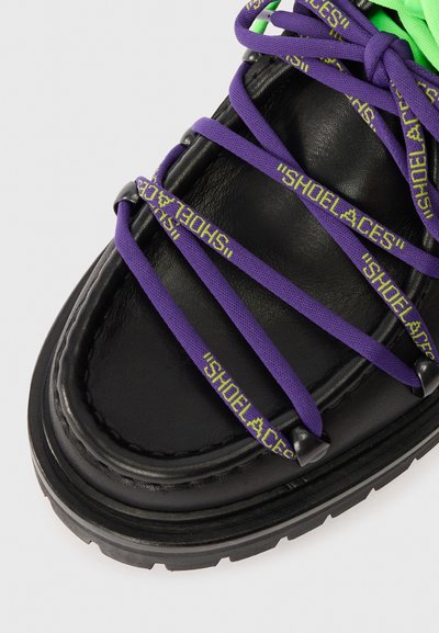 Μαύρο δερμάτινο σνακ με μωβ κορδόνια που φέρουν το κείμενο "CORDA". Παχιά καουτσούκ σόλα με λεπτομερές ράψιμο και υφές.