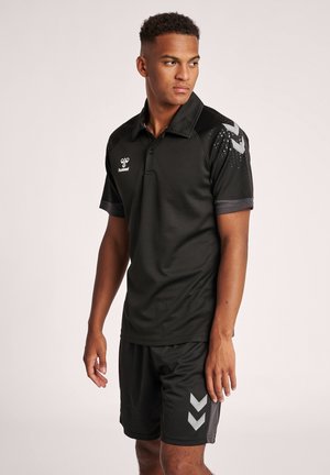 Zwart sport polo-shirt met een kraag, voorzien van textuur mouwen en zilveren chevrons. Gecombineerd met bijpassende zwarte shorts.