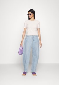 T-shirt rosa claro com nervuras, jeans de perna larga azul clara de cintura alta, bolsa roxa e sandálias de vime roxas. Estilo minimalista, linhas limpas.