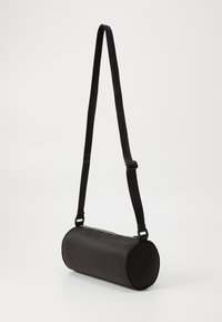 Borsa a tracolla cilindrica nera con una finitura liscia e opaca. Caratterizzata da una chiusura con zip e da una tracolla regolabile con dettagli in rilievo.