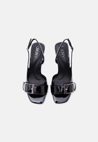 Μαύρα σανδάλια slingback από πατεντέ δέρμα με τετράγωνα δάχτυλα, φαρδιές λουριά με αγκράφες και το λογότυπο DKNY στις μαξιλαρωτές εσωτερικές σόλες.