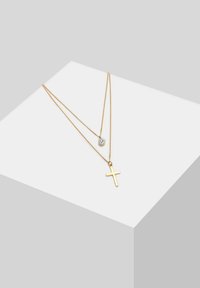 Collana in oro a strati con un piccolo ciondolo a croce e un cristallo tondo, caratterizzata da catene delicate e un finish liscio e lucido.