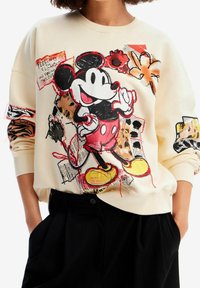 Felpa color crema con una grande grafica di Topolino in pantaloni rossi, con motivi floreali e dettagli in tecniche miste sulle maniche.
