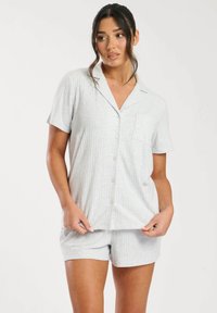 Lichtgrijze pyjam SET met korte mouwen. Verticale ribbeltextuur, knoopsluiting en zakdetails op het shirt; bijpassende shorts met elastische taille.