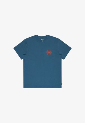 T-shirt en coton bleu avec un col rond, des manches courtes et un petit logo circulaire rouge sur la poitrine à gauche.