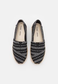Basse nere intrecciate con un motivo cucito bianco, dotate di una punta arrotondata e una suola in juta stile espadrillas. Parte superiore in tessuto morbido.