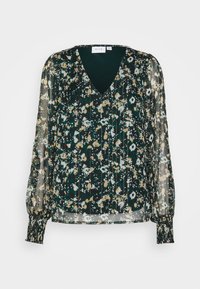Blouse à manches longues avec col en V, motif floral abstrait en vert foncé, beige et blanc, et poignets froncés sur manches en tissu transparent.
