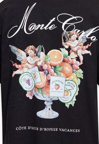 Chérubins visant avec des arcs planent au-dessus d'un bol de fruits avec des étiquettes pour fraise, pêche, orange douce et fraîcheur de vignoble sur un tissu noir avec le texte « Monte Carlo ».
