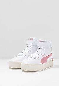 High-top sneakers with a white leather upper, pink accents, and a textured sole. Features a padded ankle support and laces.