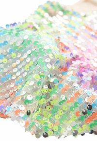 Gros plan d'un tissu transparent densément couvert de sequins ronds irisés dans plusieurs tons pastel.
