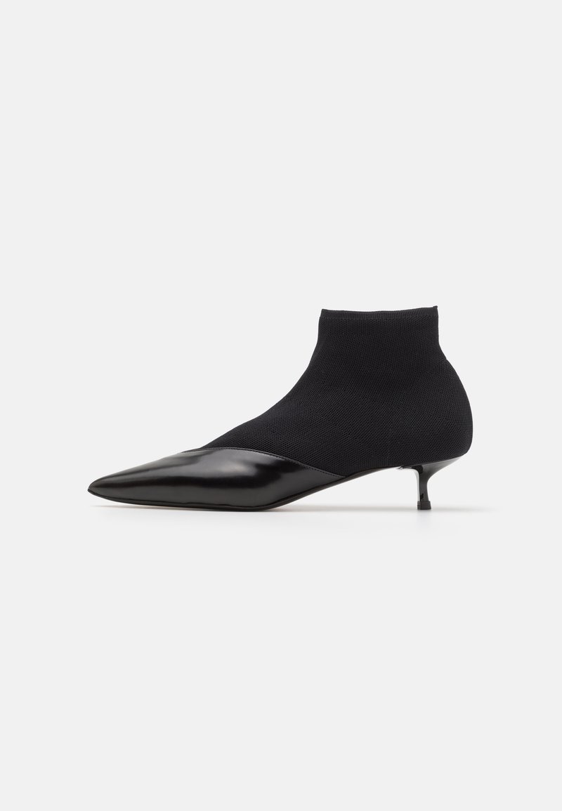 Sorte ankelstøvler med en strikket overdel og spids patenttå, med en kitten heel og et sømløst, kontureret design.